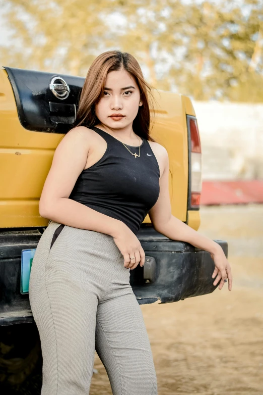 a female posing for a picture sitting on the back of a truck