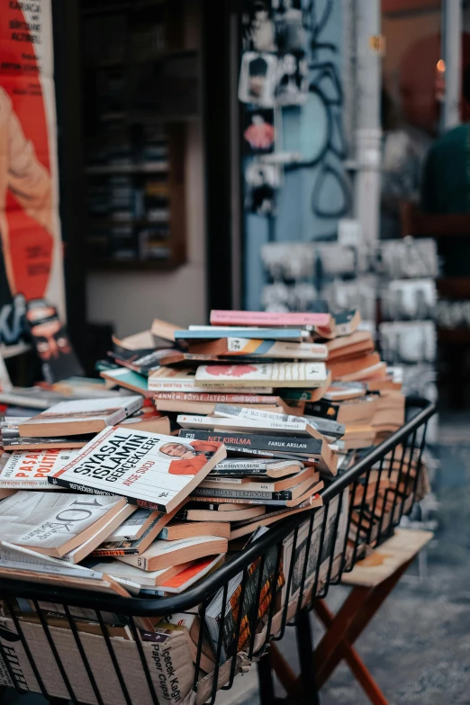 a small metal shopping cart filled with lots of books