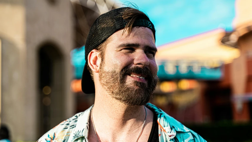 man with beard and mustache smiling with building in the background