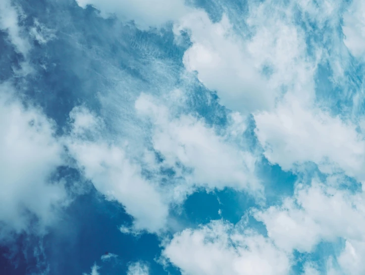 a plane flying above clouds in a blue sky