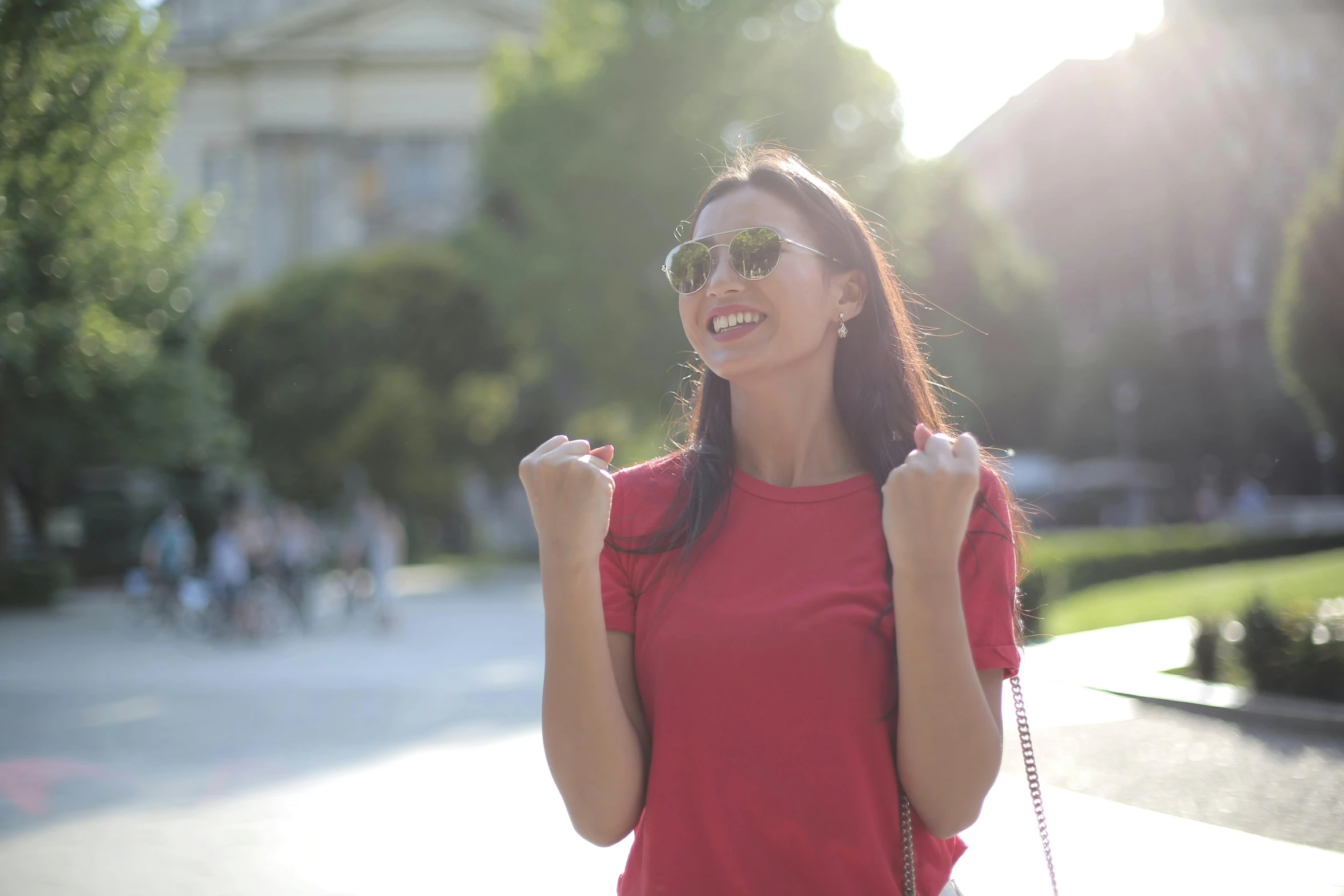 a girl standing with sunglasses on smiling at the sun