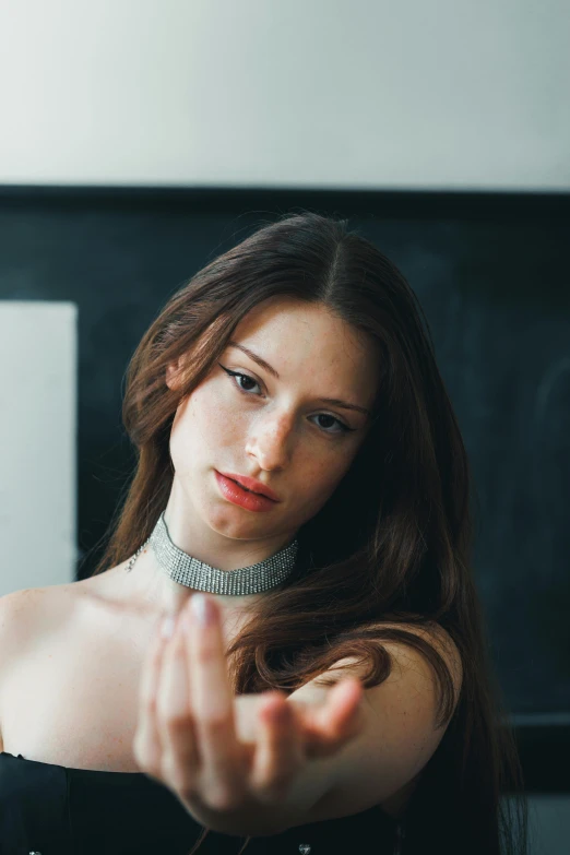 a woman wearing a choker looking down and making a face