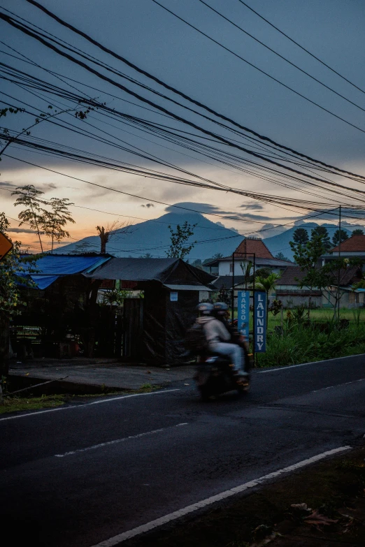 the scooter is driving down a street at twilight