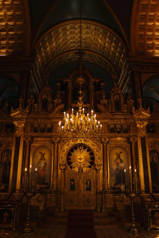 a golden altar with lit candles and a chandelier