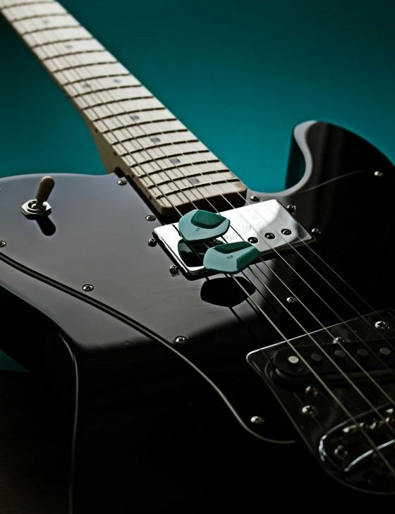 black electric guitar with white frets on green background