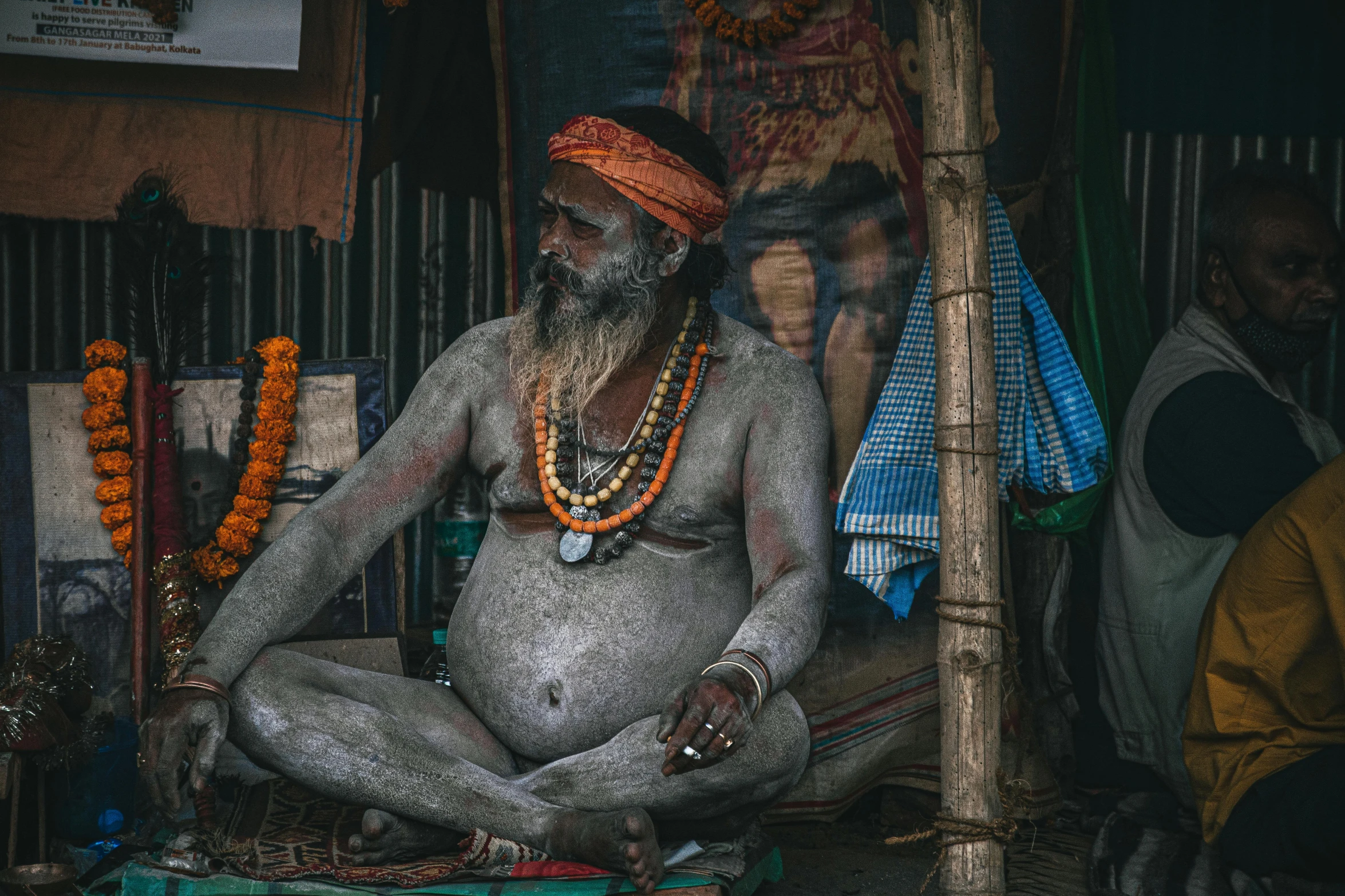 man sitting in a yoga position wearing an elaborate necklace