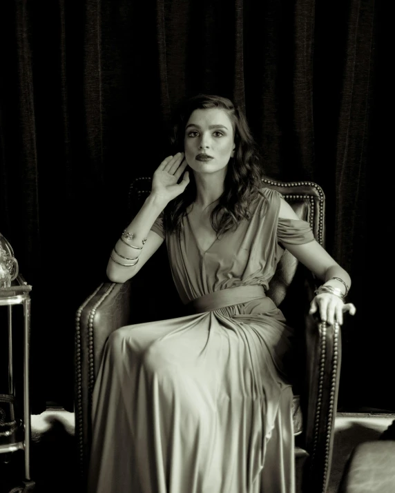 a woman is sitting in a chair with her arm resting on the pillow