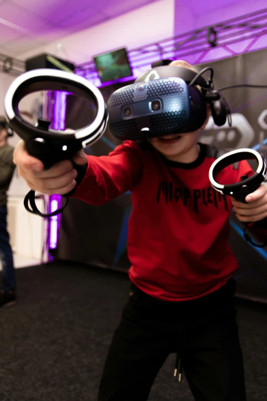 a young child with a vr headset holding two video game controllers