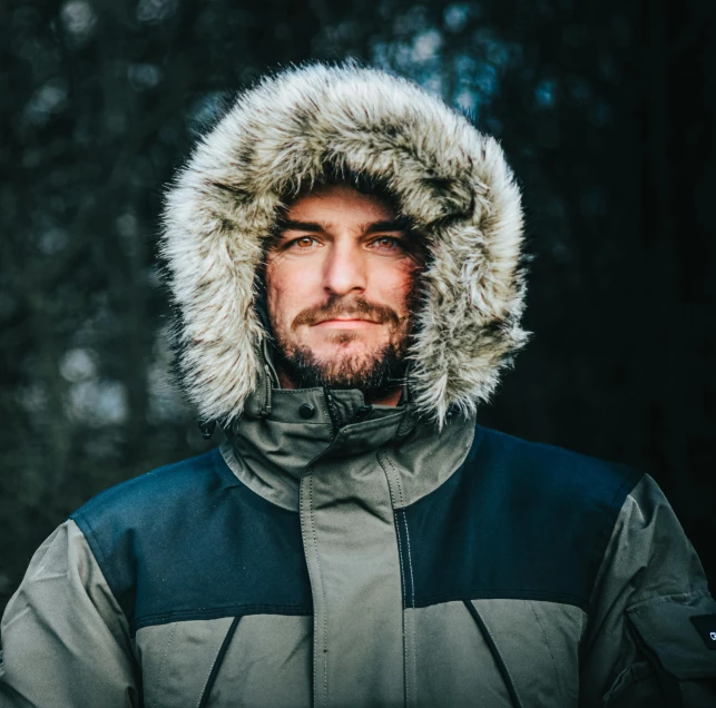 a man in the park wearing a jacket with hood on