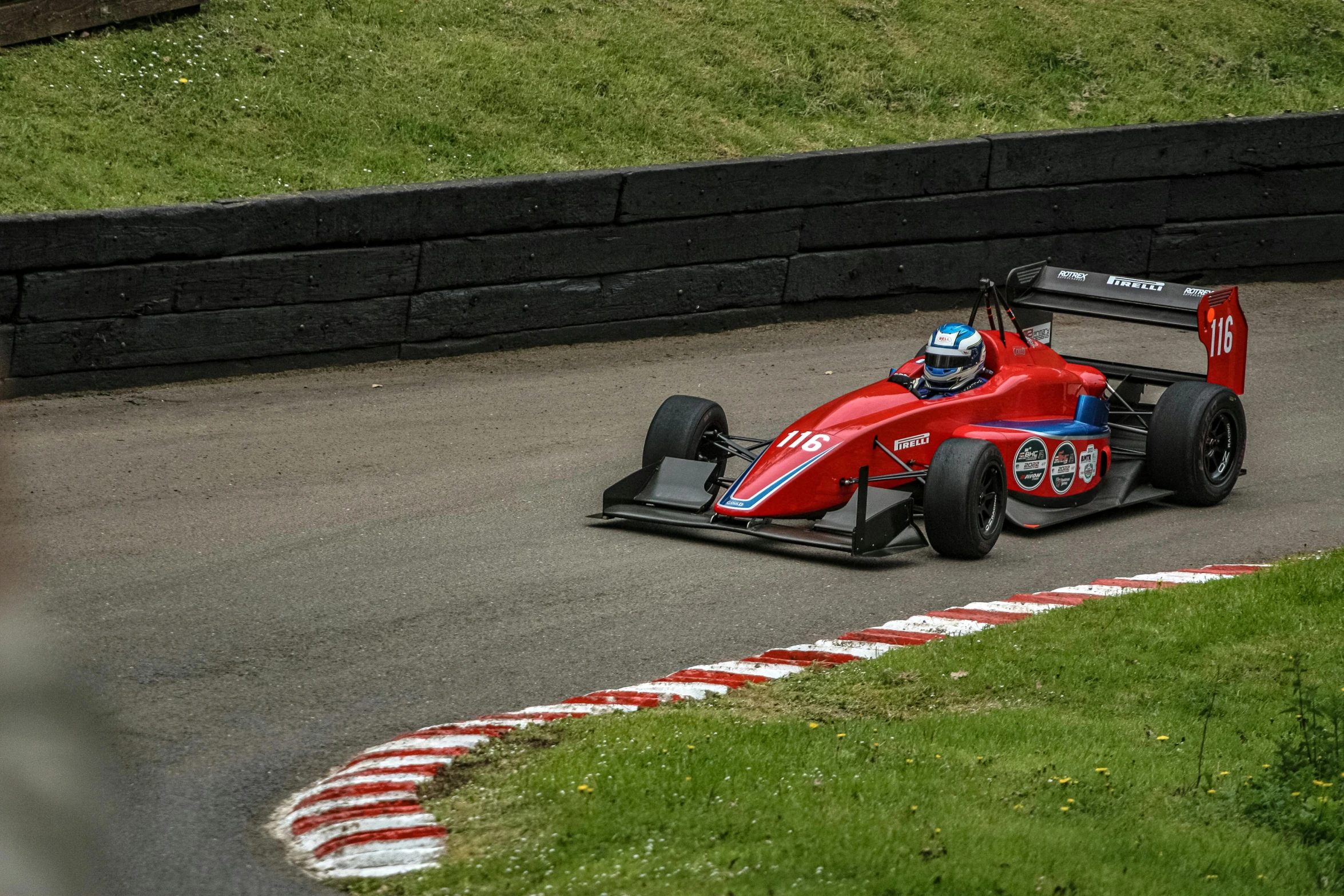 a man driving a red racing car around a track