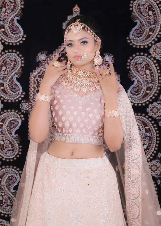 a woman is posing with her hands on her hips in a white lehenga and jewelry