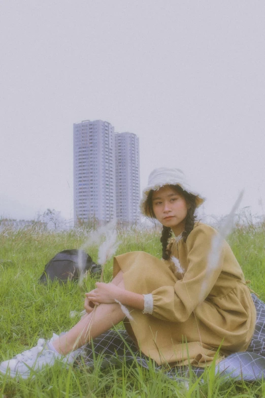 a woman with a hat sits in the grass