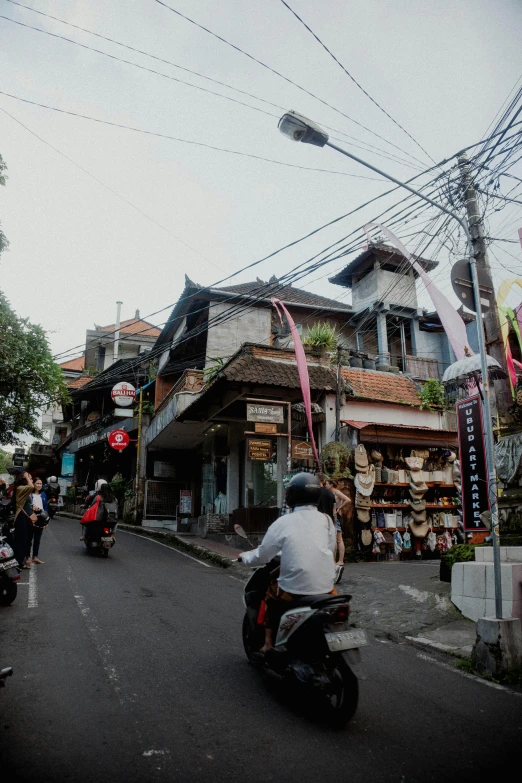 people riding motorcycles down a road between buildings