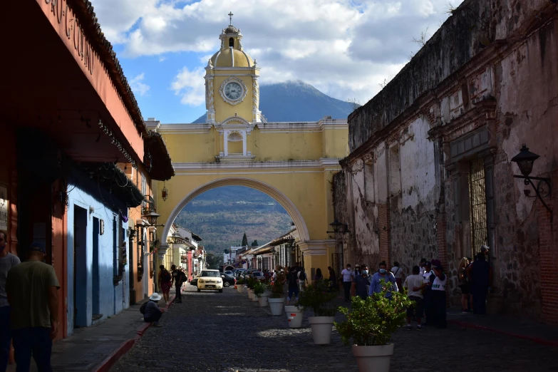 a church stands behind a yellow arch in the middle of the road