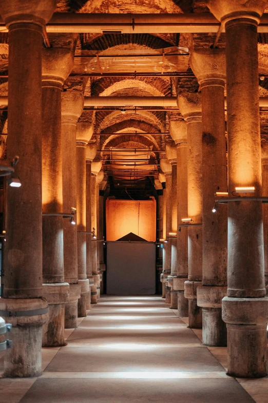 the inside of an ornate hall with columns, lights and an open doorway