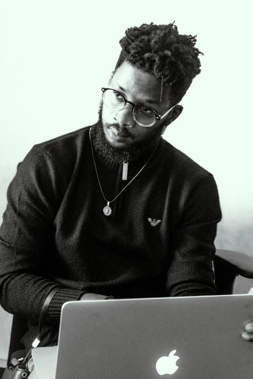 a man sitting next to his laptop looking at the screen