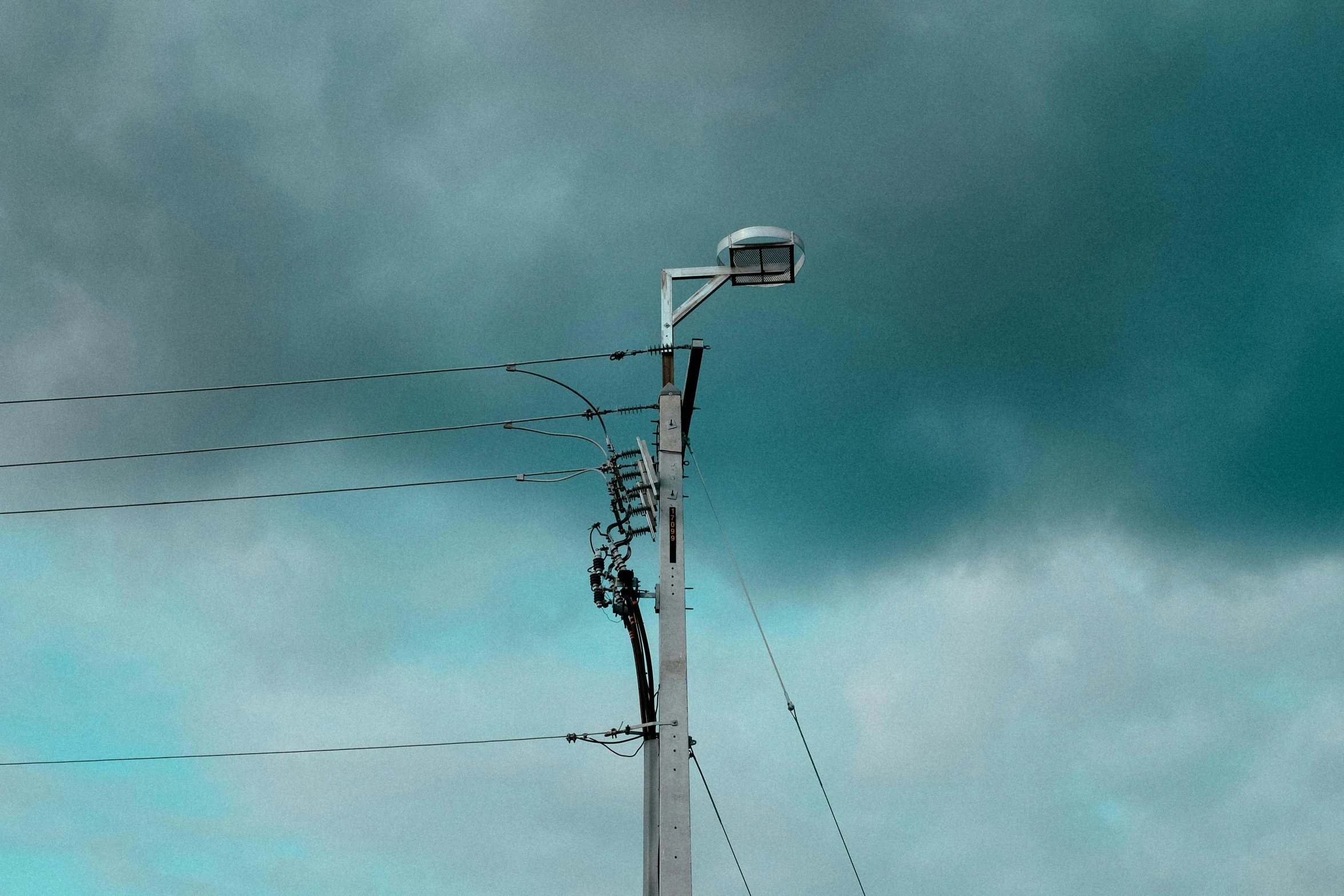 a stop sign on top of power lines under a cloudy sky