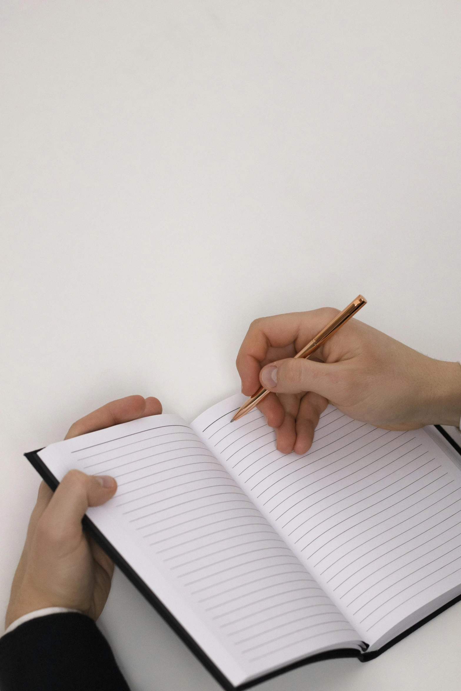 a person is holding a notebook and writing on it