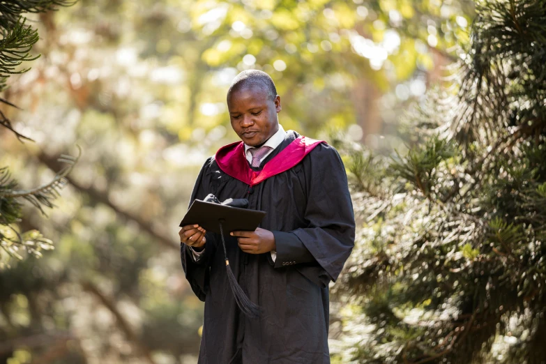 a woman in black graduation gown reading a book