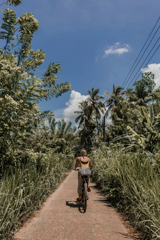 a woman riding her bike down a dirt road