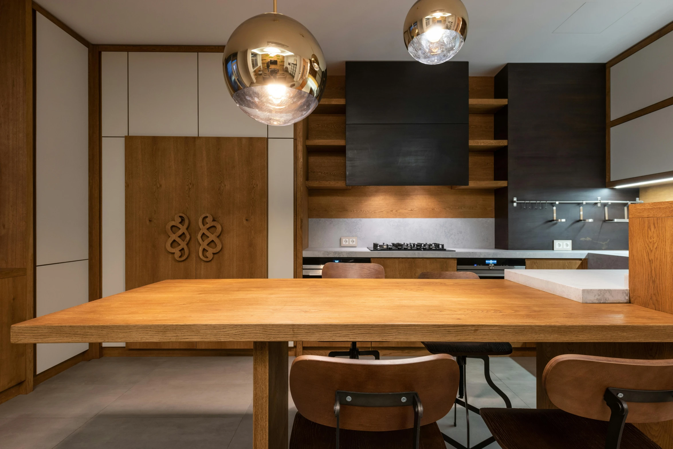 a kitchen with two suspended lights above the table