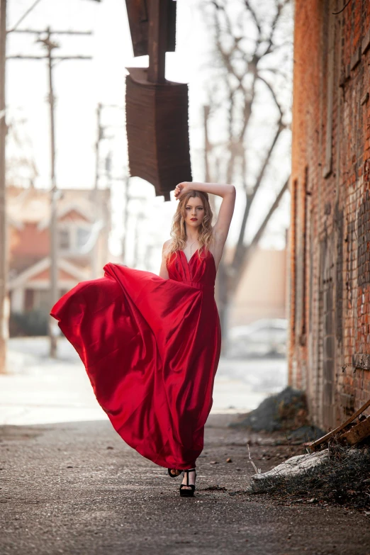 a woman in red gown walking down the road