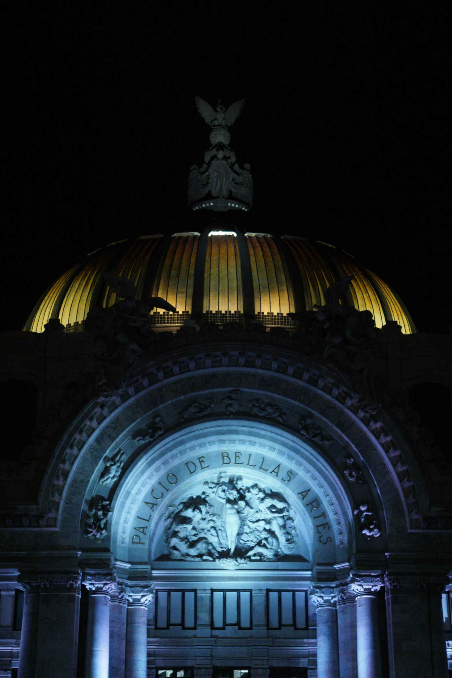 an illuminated domed building in a city with columns