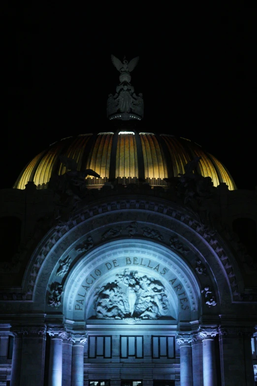 an illuminated domed building in a city with columns