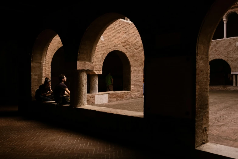 two people sitting on small seats next to arches