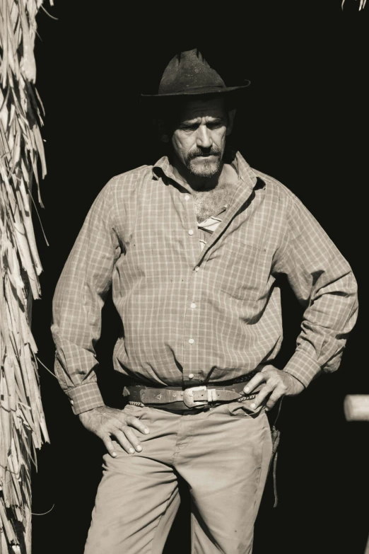 a man in a fedora and pants standing next to some grass