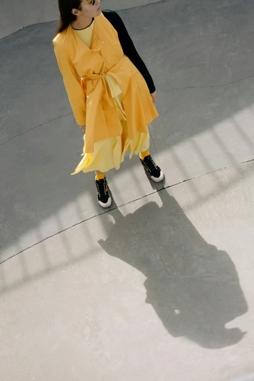 a girl dressed up in yellow standing next to a skateboard