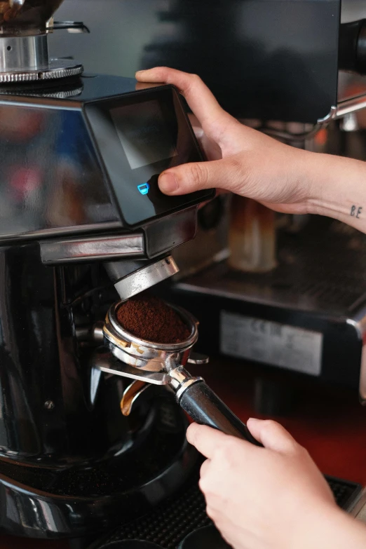 a hand holding a device in front of a coffee maker