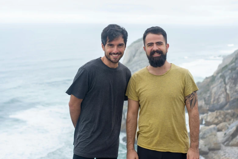 two men standing next to each other near the ocean