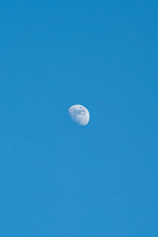 the moon in a blue sky seen from a distance