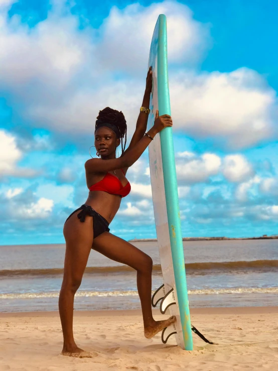 a women who is holding a surfboard on the beach