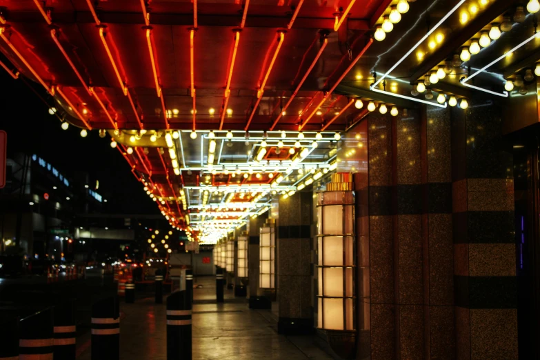 an outdoor walkway has lights hanging from it