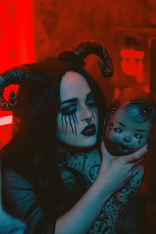 a girl with her face painted and devil makeup holding her doll