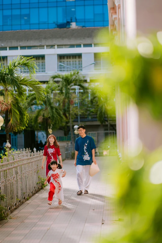 young child walking next to his mother and dad in red and blue clothes