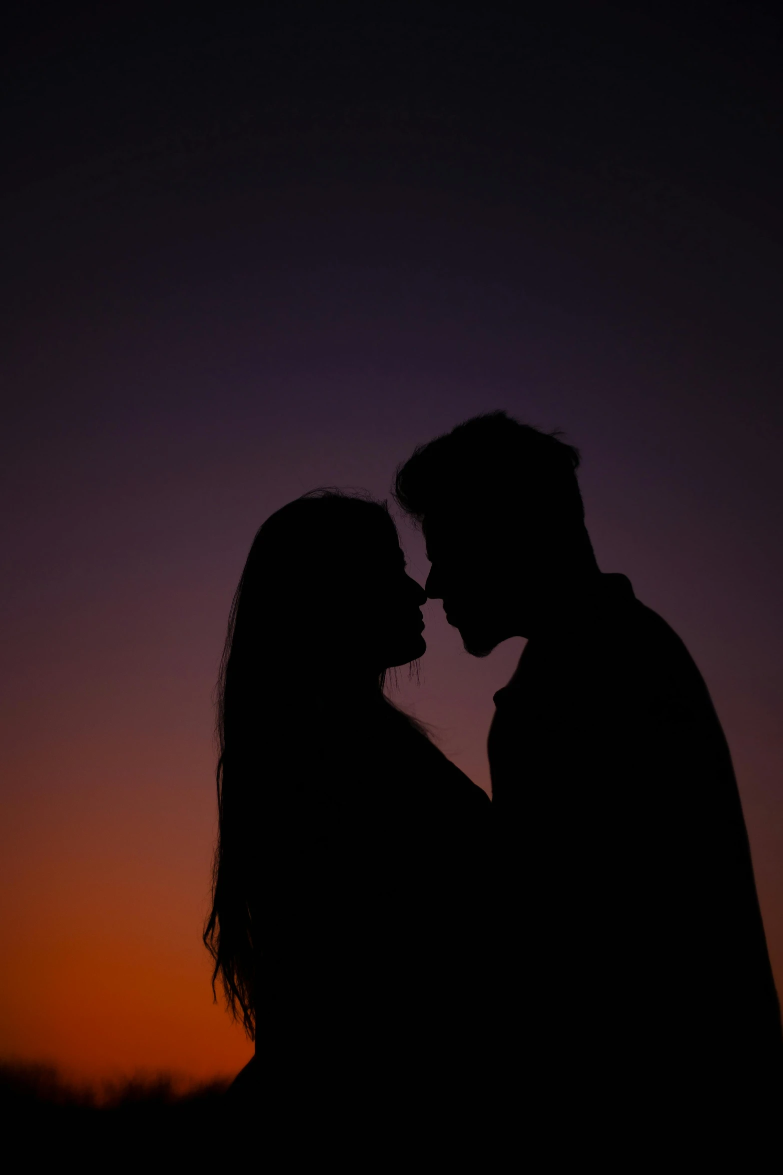 a couple silhouetted against the setting sun