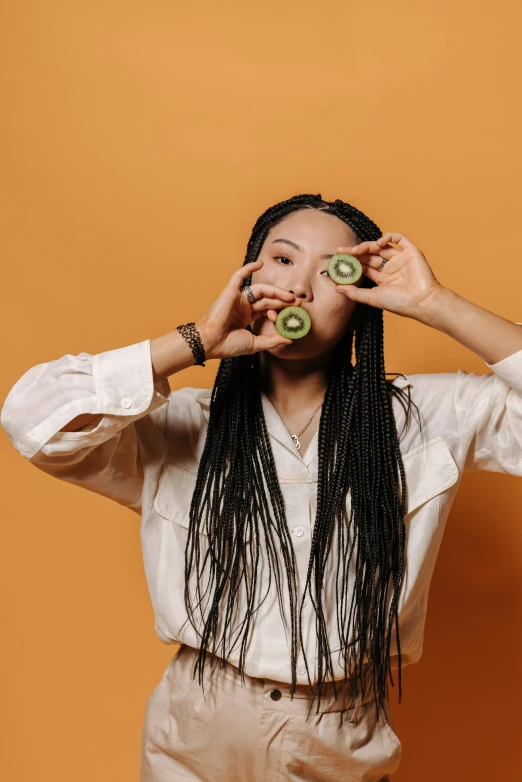 a woman holding a cucumber with her fingers to their eye