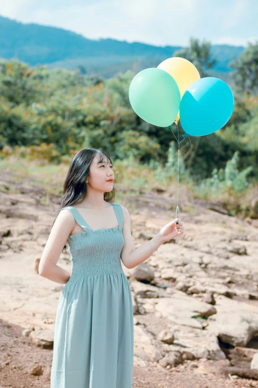 a young woman holds three balloons with an odd amount of color