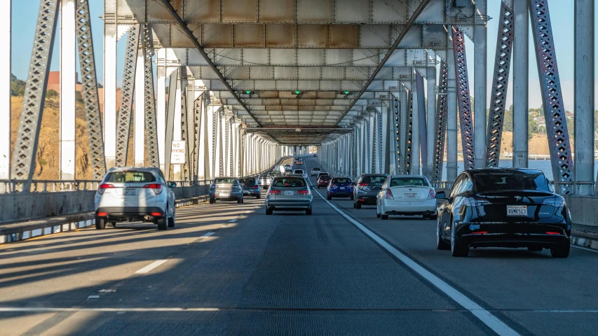 cars driving on the side of a road with metal supports