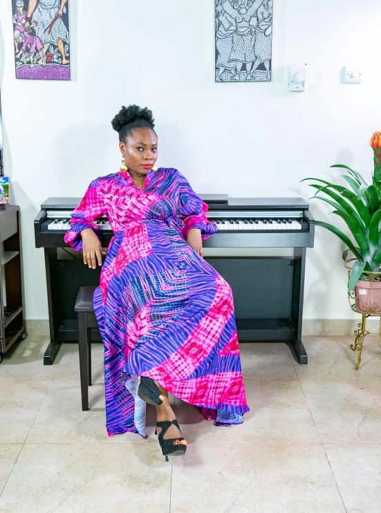 a woman in a long dress is sitting by a piano