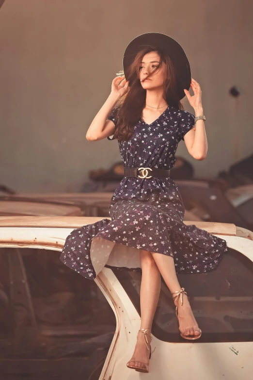 a young woman wearing a hat is sitting on top of a car