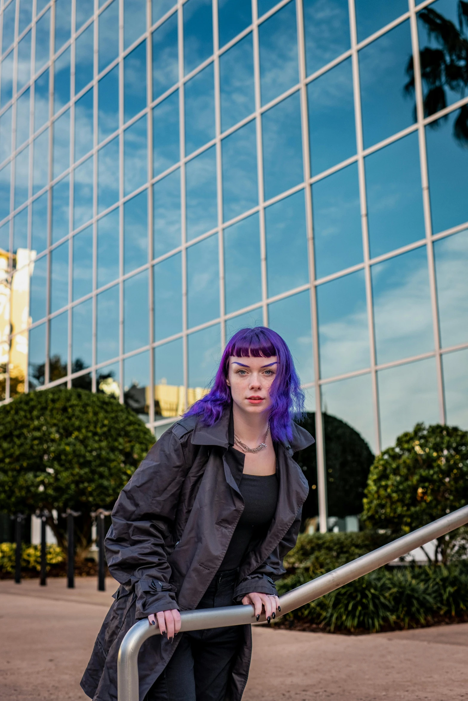 a woman with a purple and blue dyed hair sitting on a railing