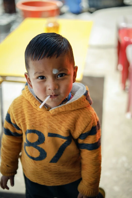 a boy in orange jacket with yellow hoodie and nose piercing