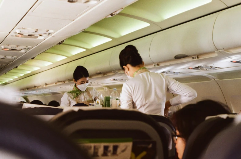 two people in masks on the aisle of an airplane