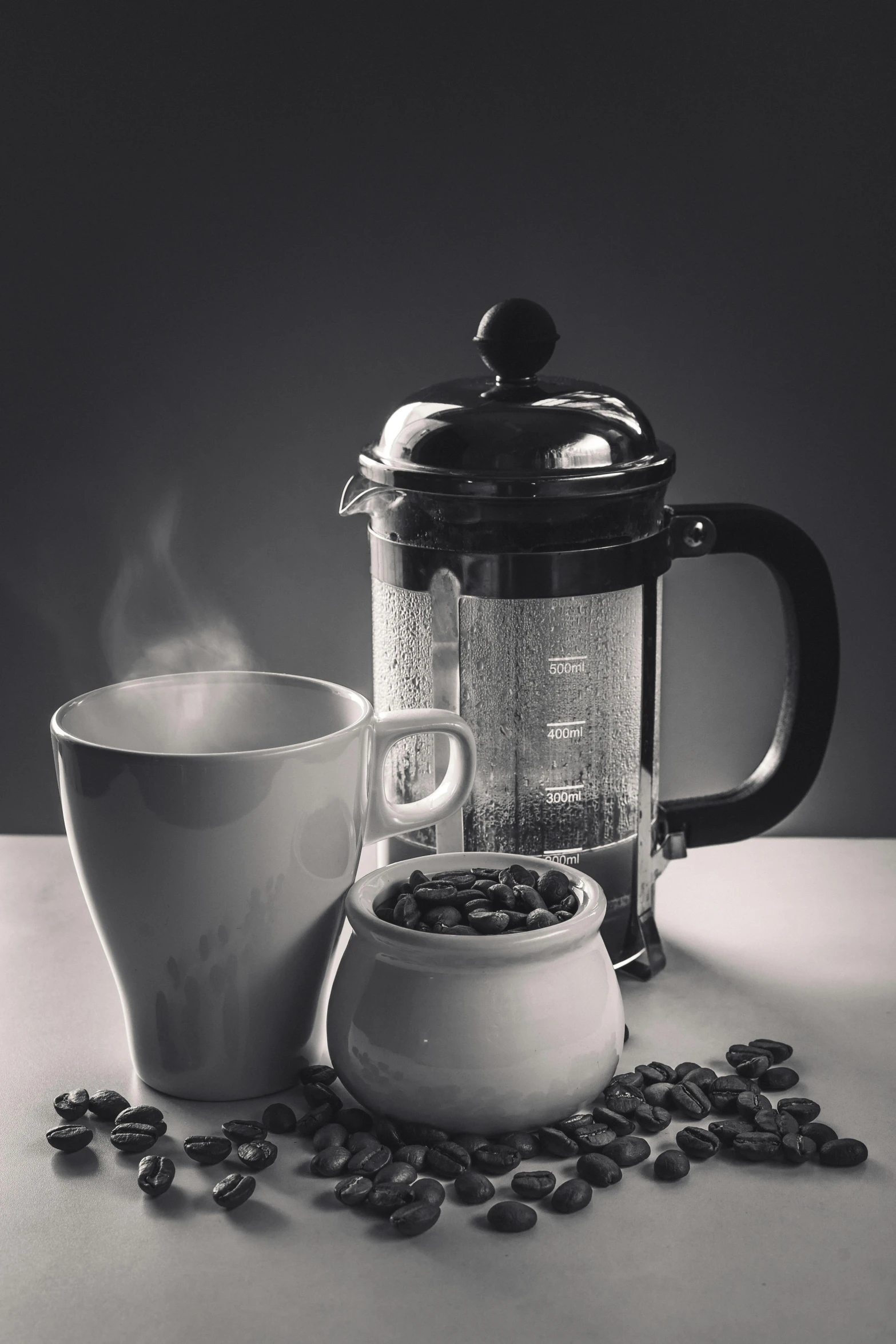 a cup of coffee sitting next to a tea pot with a glass