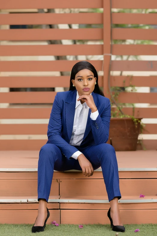 a woman wearing a blue suit is sitting on some steps