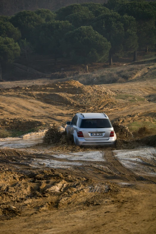a white suv driving through a muddy field